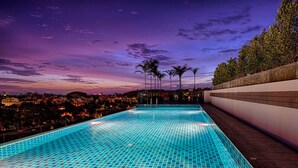 A swimming pool with a tiled floor and a view of the city at dusk. - Kata Beach Ozone Superb Fully Equipped Studio Kitchen Washing Machine air con (Karon)