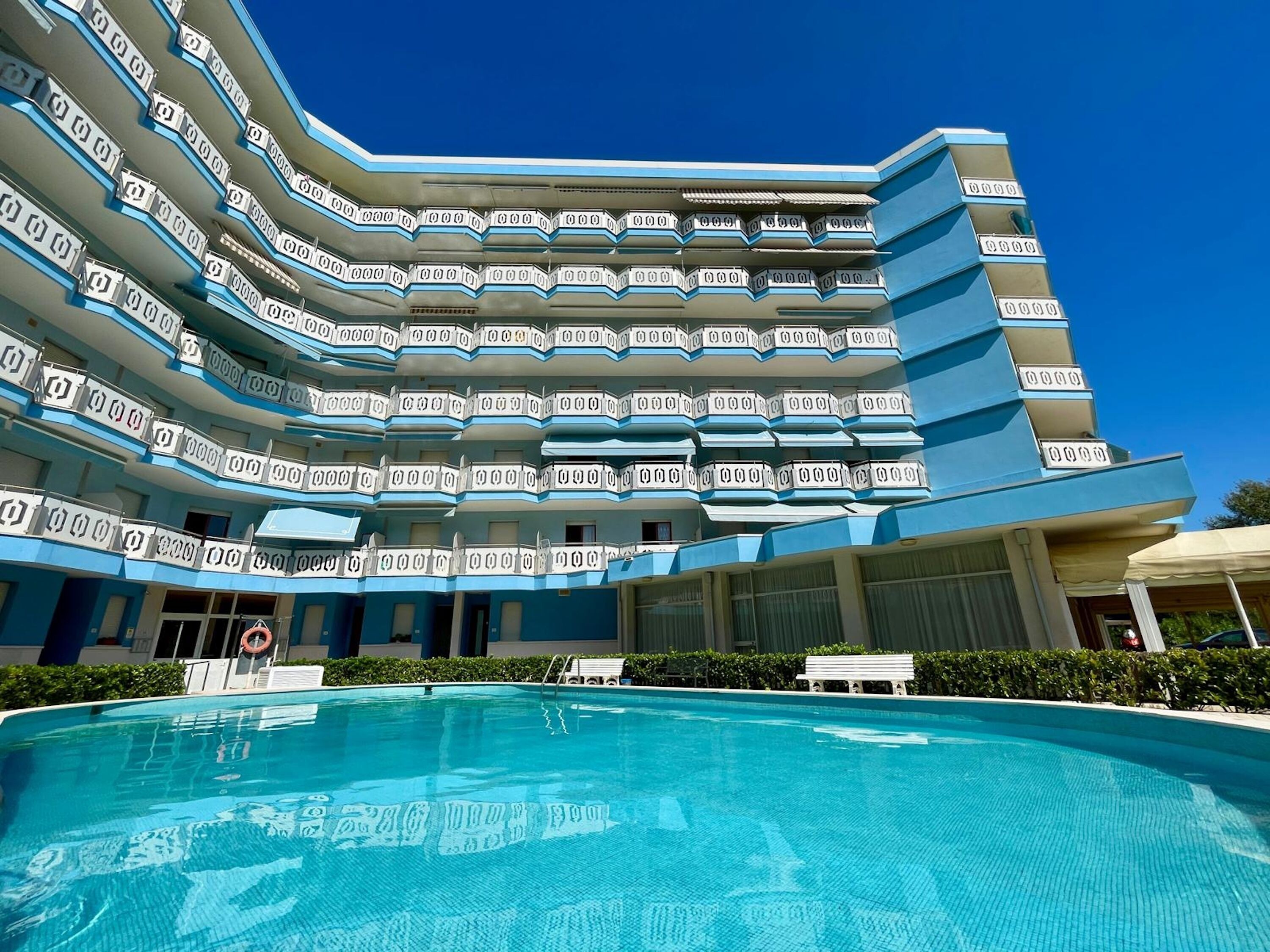 Un hôtel à plusieurs étages avec une piscine en premier plan.