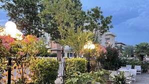 An outdoor area with potted plants, seating, and buildings in the background. - Hotel Sara - 2 Guests Room - n 13 (Cesenatico)