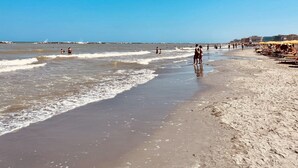 A beach with people walking along the shore, umbrellas, and beach chairs. - Hotel Sara - 2 Guests Room - n 13 (Cesenatico)