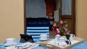 Une pièce chaleureuse avec un canapé bleu, une table en bois sur laquelle se trouve un plateau de produits pour le petit-déjeuner, et un ordinateur portable.