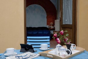 Relax in this charming room with a sofa against a brick wall, featuring a bathroom with a radiator and a wooden tray with a teapot, cups, and a vase.