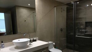 A modern bathroom with a large sink, toilet, and glass shower enclosure. - One Bedroom, Great Location Steps From the Beachh, Beautiful Roof Top View! (Playa del Carmen)