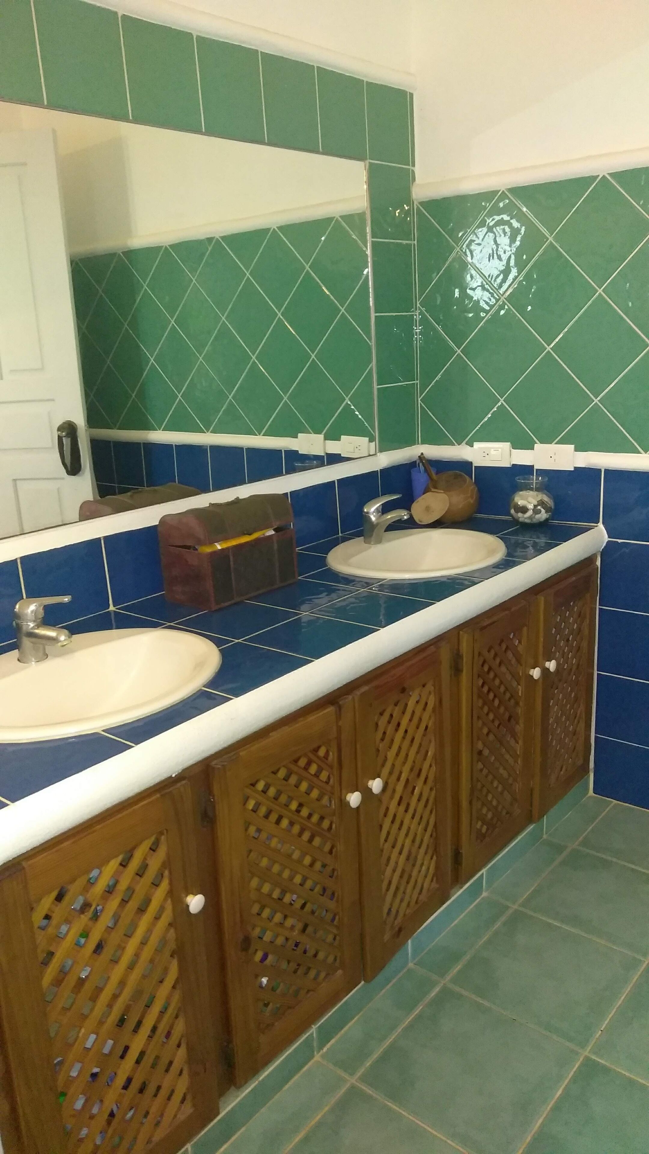 Casa de banho com duas pias, um espelho e um armário com frascos.