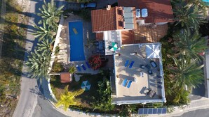 Vista aérea de uma propriedade residencial com piscina, espreguiçadeiras e área de varanda coberta.