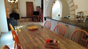 Uma área de refeições com uma mesa de madeira, cadeiras laranjas e uma placa de identificação.