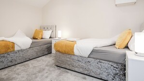 Een moderne slaapkamer met twee bedden, een nachtkastje en een bedtafeltje.