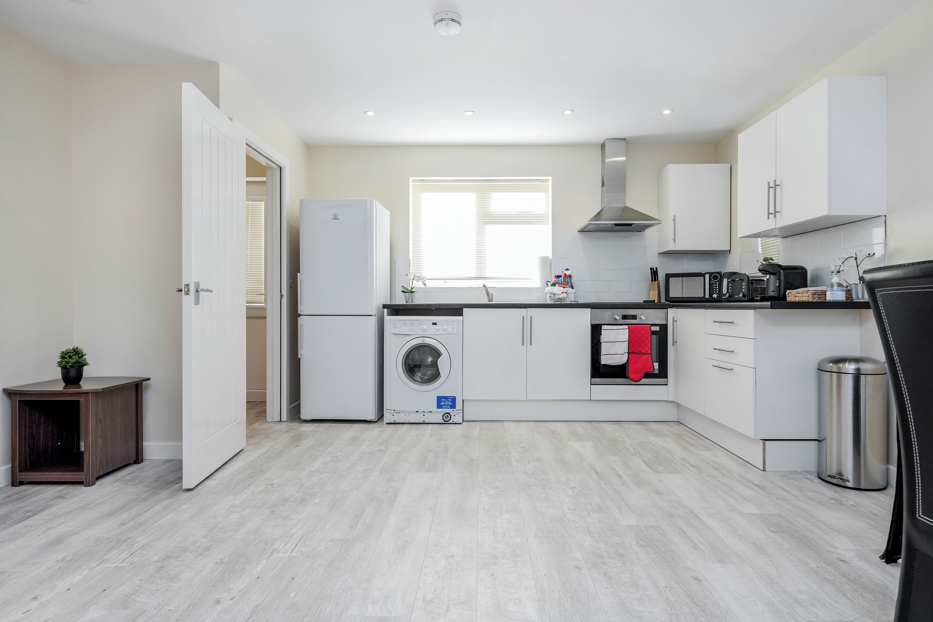 A modern kitchen with a washing machine, microwave, and oven.