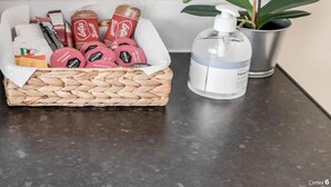 Een aanrecht met een gevlochten mand met verschillende verpakte producten, een fles handdesinfecterend middel en een potorkidee.