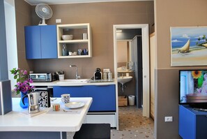 Une cuisine de taille réduite, équipée d’un four à micro-ondes, d’un évier et de meubles de couleur bleue.