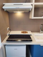 Una cucina moderna con piano cottura integrato, una cappa aspirante bianca e un piccolo lavello.