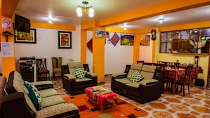 A living room with sofas, a coffee table, and a dining area with a table and chairs. - Intitambo Three Star Hotel With Panoramic View of the Mountains (Ollantaytambo)