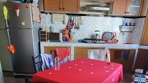Una cocina con armarios de madera, una mesa roja y piso de baldosas.
