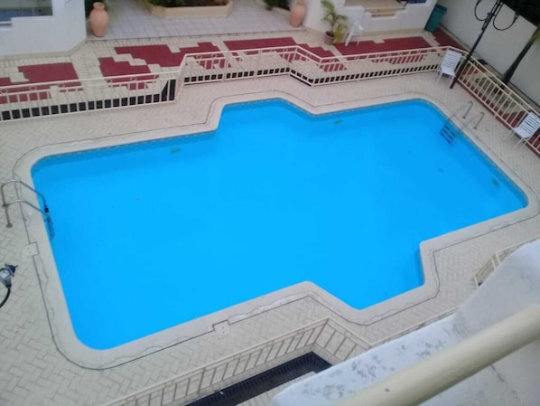 A rectangular swimming pool with a tiled deck and a white fence surrounding it. - Room-roommate for Rent in Flic en Flac (Black River)