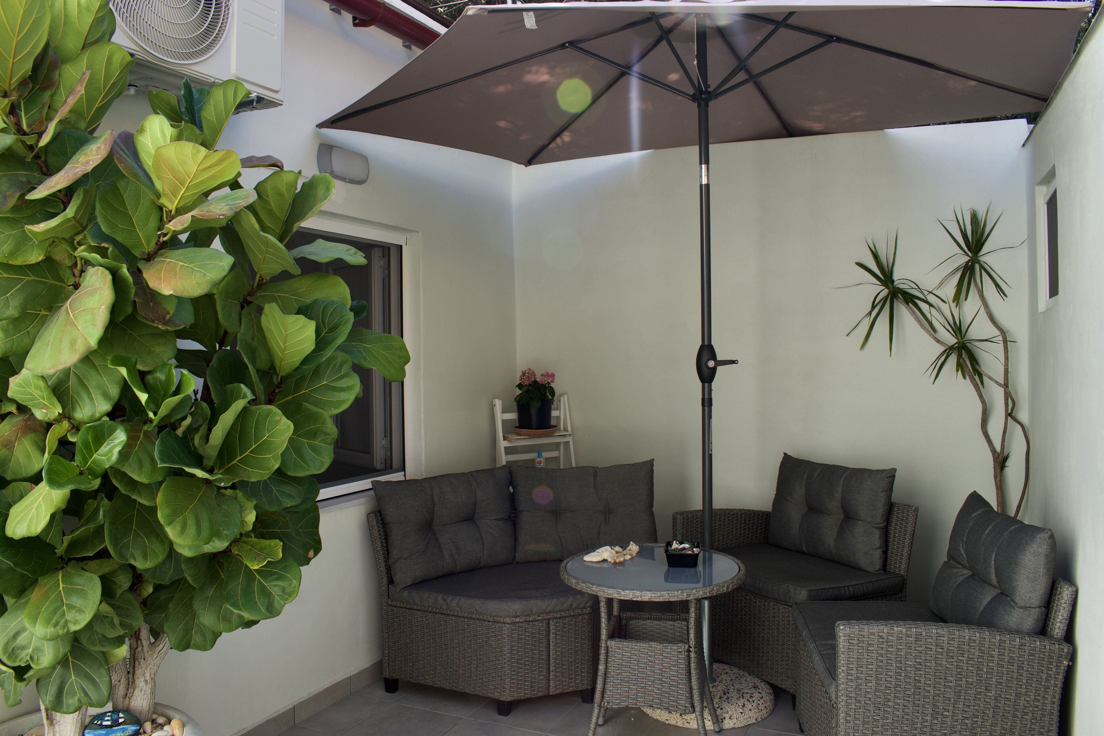 Een zithoek met een comfortabele bank, een ronde tafel en een parasol.
