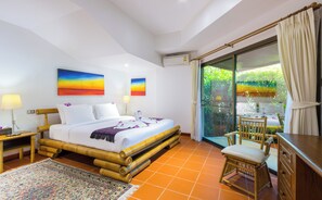 Relax in a spacious room with a large bed, comfortable seating area, and balcony overlooking the surrounding greenery.