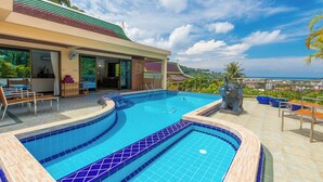 A swimming pool with a tiled edge, a statue, and outdoor seating. - Luxury Four Bed Villa Jasmine, Infinity Pool, Full Staff , Chef and Breakfasts (Karon)