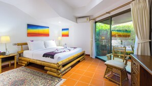 A hotel room with a bed, a desk, a chair, and a view of greenery through a glass door. - Luxury Four Bed Villa Jasmine, Infinity Pool, Full Staff , Chef and Breakfasts (Karon)
