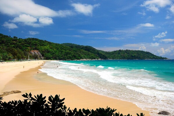 Escape to a serene beach surrounded by lush green hills and calm waters.