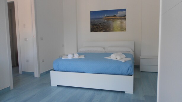 A bedroom with a bed, a painting on the wall, and a door leading to another room. - The Home of Athena Paestum (Capaccio-Paestum)