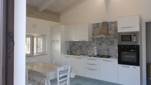 A kitchen with white cabinets, a tiled backsplash, a gas stove, and a built-in oven. - The Home of Athena Paestum (Capaccio-Paestum)