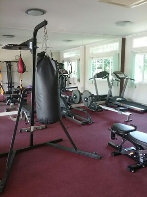 Uma academia com diversos equipamentos de exercício, incluindo um saco de pancada, esteiras e aparelhos de musculação.