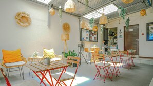 A room with tables and chairs, a ceiling fan, and hanging plants. - Manzil Anilao Cosy 2 Bedroom Apartment U2 (Mabini)