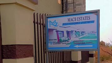 Letrero de Macb Estates que anuncia apartamentos completamente amoblados, con información de contacto.