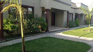 A residential building with a paved walkway, palm trees, and well-maintained lawns.