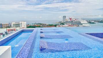 A rooftop infinity pool with a view of the sea and a cruise ship in the background.