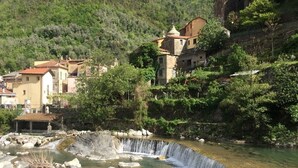 A natural water feature with a waterfall, surrounded by greenery and buildings. - Cozy 45 Sqm Apartment Badalucco Comfort Nature (Badalucco)