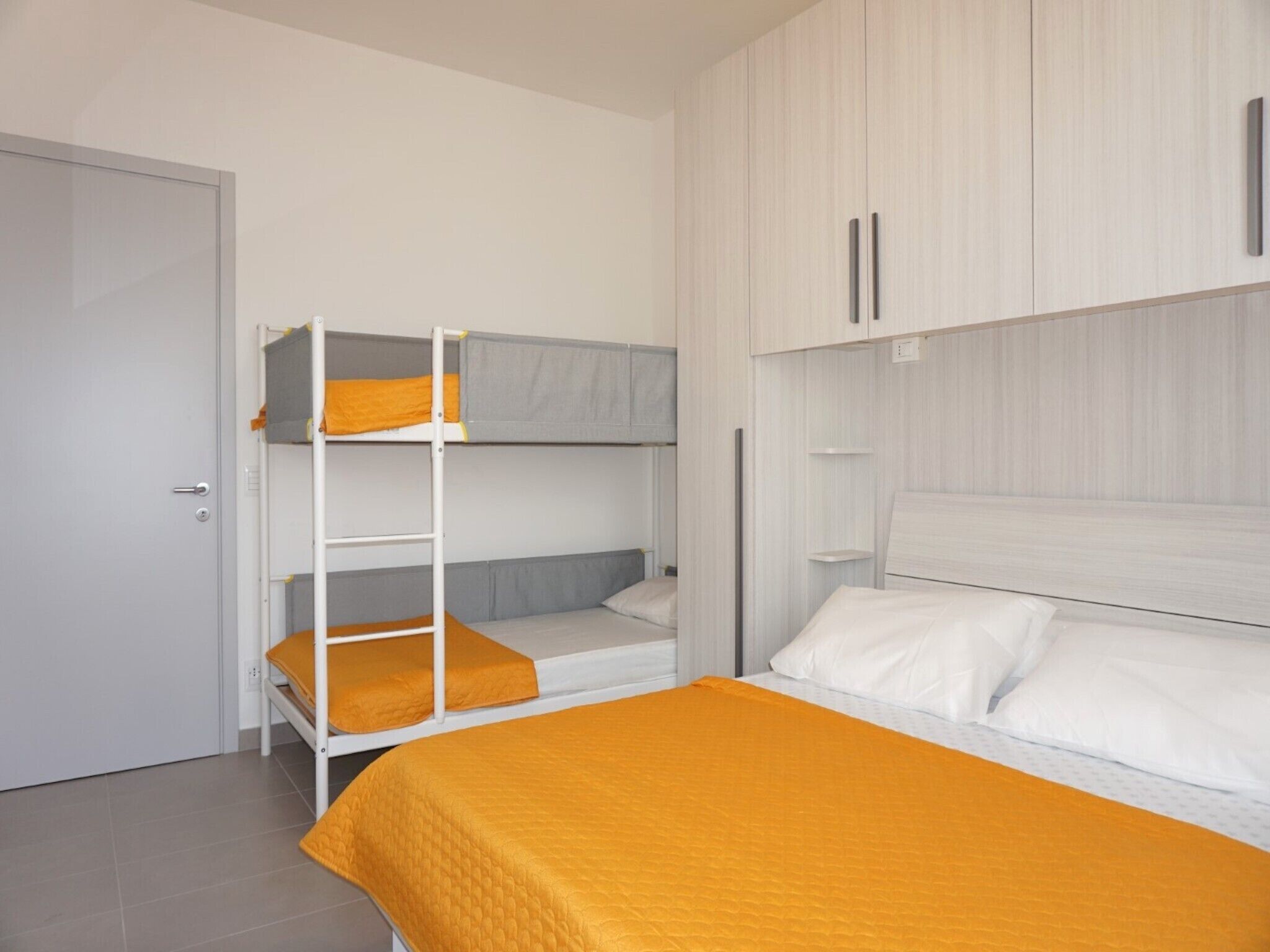 Ein Schlafsaalzimmer mit Etagenbetten, einem Kleiderschrank und einer Tür.