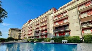 A multi-story residential building with a swimming pool in the foreground. - Lovely Flat With Balcony (Caorle)