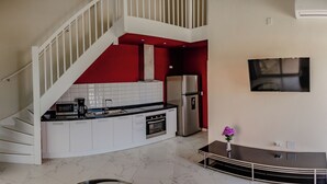A modern kitchen with white cabinets, a stainless steel refrigerator, and a built-in oven.