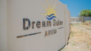 A sign for Dream Suites Aruba with a sun and wave design.