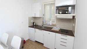 A compact kitchen with white cabinets, a stainless steel sink, a microwave, and a small countertop. - Hanna One-bedroom Apartment (Rovinj)