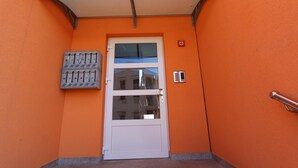 An orange building with a white door, a mail slot, and a fire alarm. - Hanna One-bedroom Apartment (Rovinj)