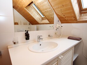 A bathroom with a white sink, a mirror, a towel, and a hairdryer. - You Will Like This Home in the Harz Mountains (Oberharz am Brocken)