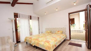 A bedroom with a large bed, a bedside table, a lamp, and a view of the outside. - Rovinj-home Studio (Rovinj)