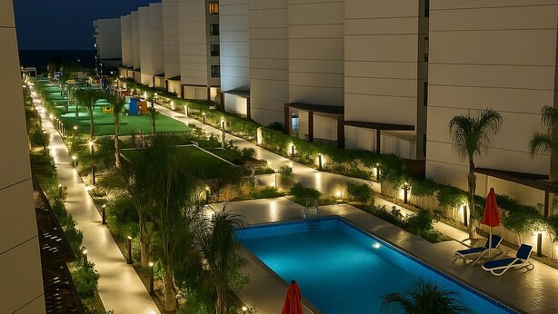 A nighttime view of a hotel pool area with a swimming pool, lounge chairs, and palm trees. - Peaceful Stay by Sea (Al-Manasrah)