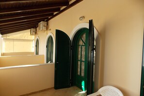 A hallway with a green door, a white chair, and a window with a view. - The Executive - Heartbreaking sea and Landscape in Corfu - Greece (Corfu)