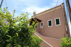 A building with a satellite dish, two windows with shutters, and a satellite dish on the roof. - The Executive - Heartbreaking sea and Landscape in Corfu - Greece (Corfu)