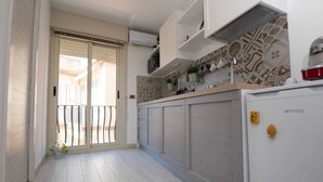 Una cocina moderna con puerta corrediza que da a un balcón, microondas integrado y refrigerador con un logotipo.