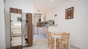 Una cocina moderna con armarios blancos, una mesa de comedor con sillas y una pequeña planta en maceta sobre la encimera.