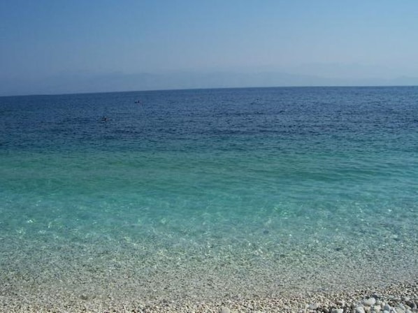 Ein freier Blick auf einen Kiesstrand, der zu ruhigem Seewasser führt.
