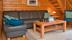 A cozy log cabin interior with a leather sofa, a wooden coffee table, and a framed picture on the wall. - Come to This House to Stay for Holidays (Oberharz am Brocken)