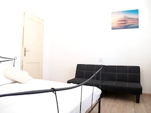 Um quarto com uma cama, um sofá preto e uma porta.