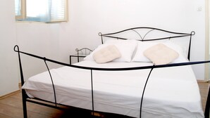 A single bed with a metal frame, white bedding, and two pillows. - Step Away From The Beach 1-bedroom Apartment Lolov (Preko)
