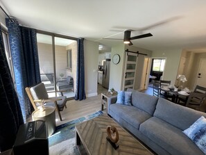 Ein modernes Wohnzimmer mit einem grauen Sofa, einem Couchtisch und einem Essbereich mit Tisch für vier Personen.