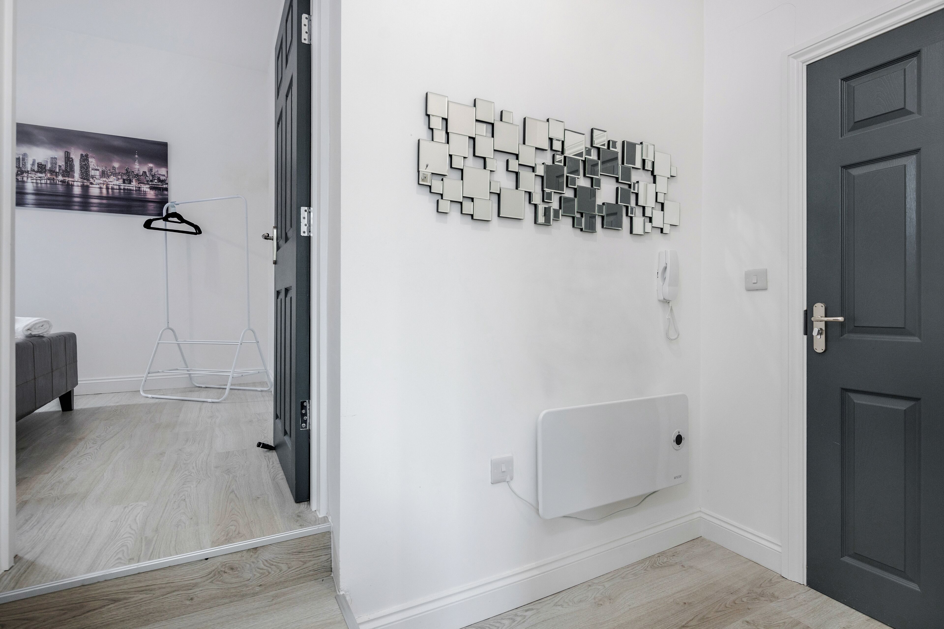 A hallway with a mirror wall art, a radiator, and a door.